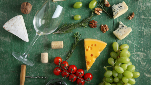 cheeses, grapes and tomatoes with empty glass